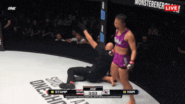 a woman in a purple tank top is standing next to a referee in a boxing ring