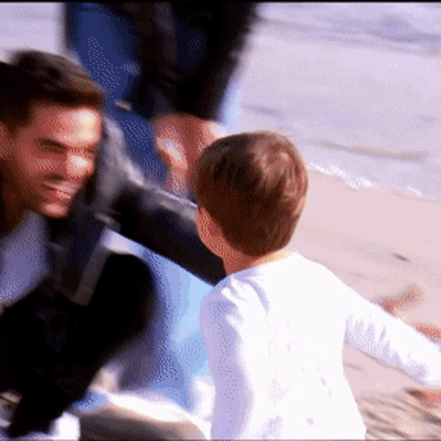 a man and a boy are playing in the sand on the beach
