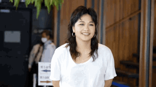a woman in a white shirt is smiling in front of a sign that says ' stairs '