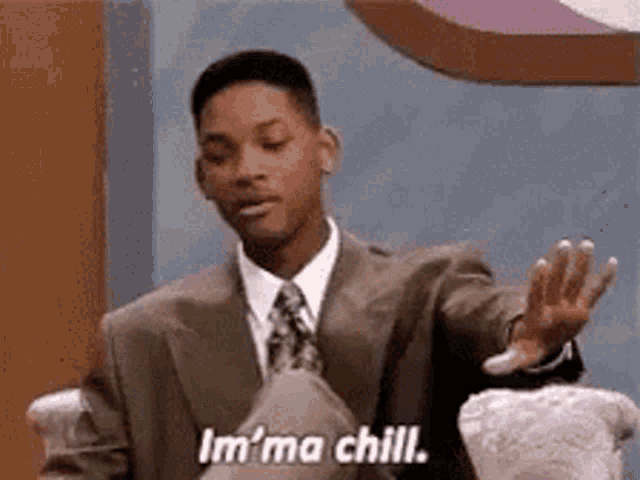 a man in a suit and tie is sitting in a chair and saying i 'm ma chill .