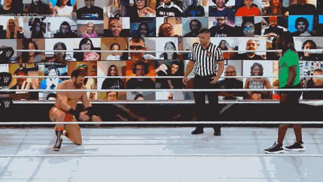 a man in a green shirt is kneeling down in front of a referee in a wrestling ring with a crowd watching