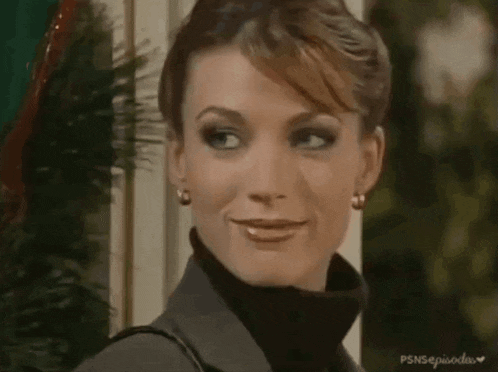 a woman wearing a black turtleneck sweater and earrings is smiling