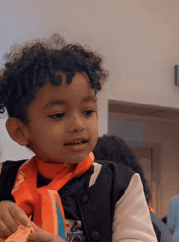 a young boy wearing an orange scarf and a black jacket
