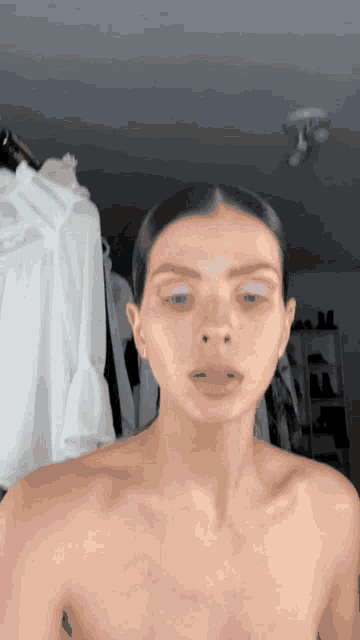 a woman without a shirt has pink eye shadow on her eyes