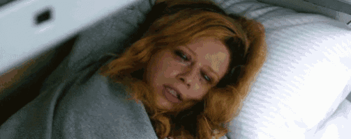 a woman is laying in bed with a pillow and a blanket .