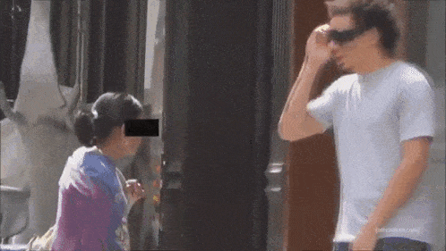 a man wearing sunglasses is talking to a woman while a woman looks on .