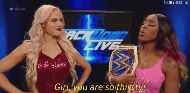 two women are standing next to each other and one of them is holding a championship belt .