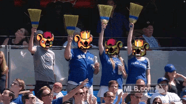 a group of blue jays fans holding up brooms in the stands