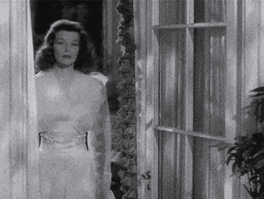 a woman in a white dress stands in a doorway