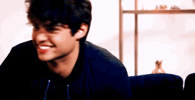 a young man is smiling while sitting on a couch in a living room .