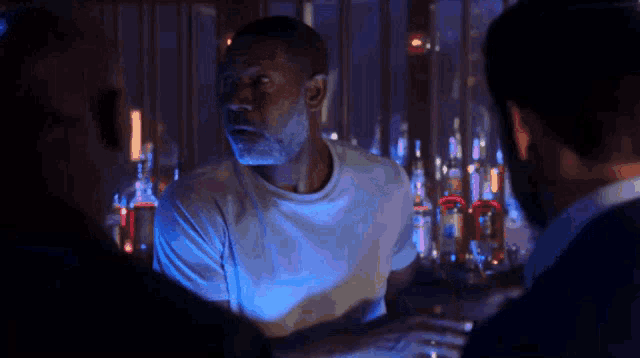 a man in a white shirt is talking to another man