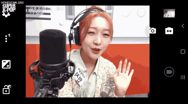 a woman wearing headphones stands in front of a microphone with the words honeycam.org on the bottom of the screen