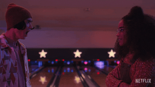 a man and a woman are standing in a bowling alley with the words " how dare you " on the screen