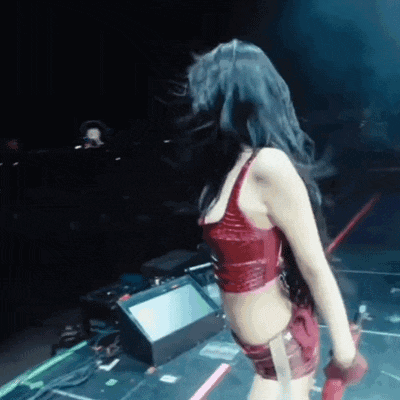 a woman in a red crop top and shorts is standing on a stage holding a microphone .