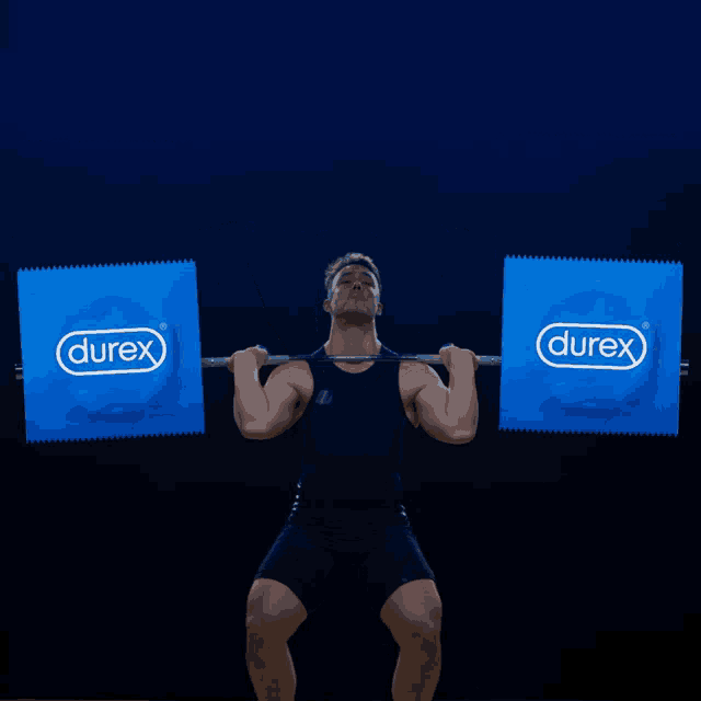 a man is lifting a barbell in front of two packages of durex