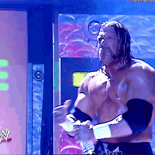 a shirtless wrestler is standing in front of a sign that says ' the next thing ' on it
