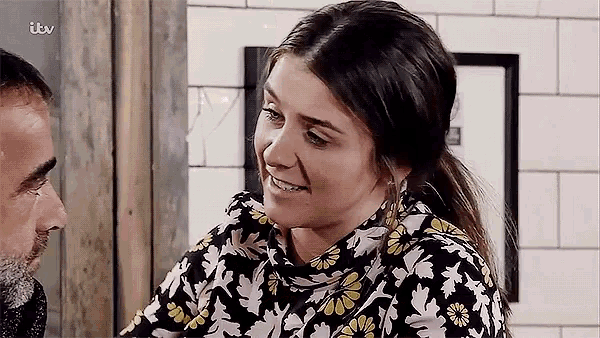 a woman is smiling while looking at a man in a kitchen .