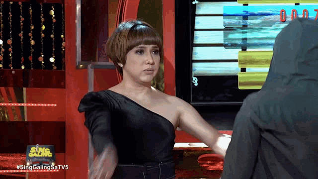 a woman in a black dress is standing in front of a screen that says sing galing sa tv5