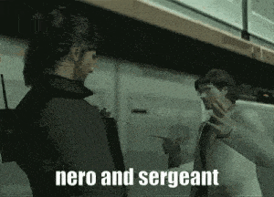 two men are standing next to each other in a room and one of them is holding a gun .