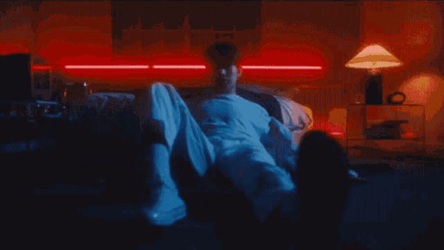 a man in a white shirt is laying on a bed in a dark room .
