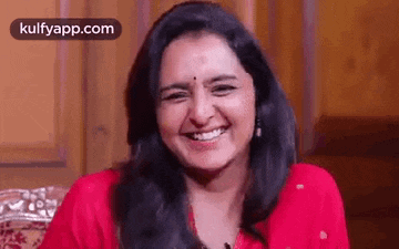 a woman is smiling while sitting on a couch .