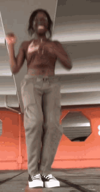 a woman in a crop top and cargo pants is dancing