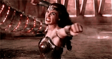a woman in a wonder woman costume is holding a fist up in the air .