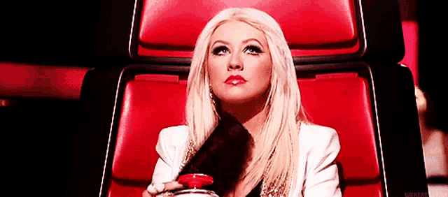 a woman is sitting in a red chair holding a red button in her hand