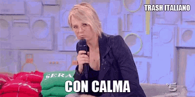 a woman is sitting on a couch holding a microphone and says con calma