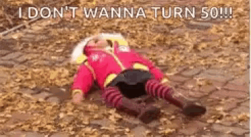 a baby is laying on the ground in a pile of leaves and says `` i don 't wanna turn 50 '' .
