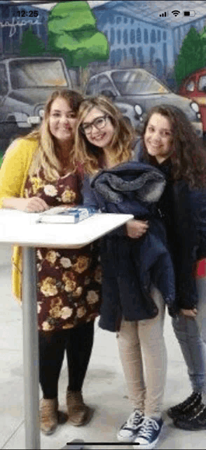 three women are posing for a picture while standing next to each other .