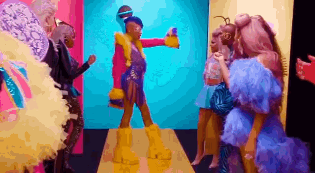 a group of drag queens are standing on a runway in a room .