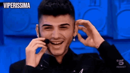 a man is wearing a headset and smiling while talking on a phone .