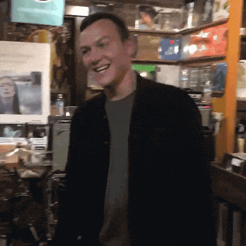 a man wearing a black jacket is smiling in a room