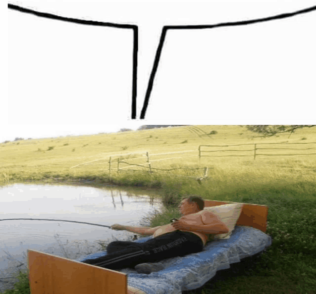a man is laying on a bed next to a body of water with a fishing rod