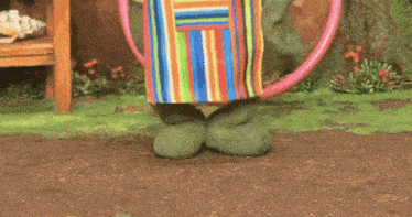 a green frog wearing a chef 's hat and apron is holding a pink hula hoop