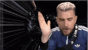 a man wearing a blue adidas shirt is making a gesture