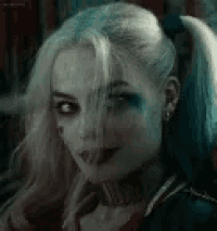 a close up of a woman wearing a harley quinn costume sticking out her tongue .