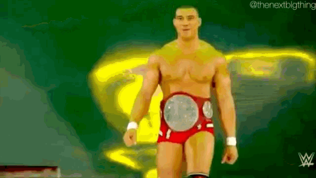 a man without a shirt is walking on a stage with a wrestling belt .