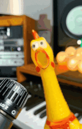 a yellow rubber chicken is standing next to a keyboard with the number 0 on it