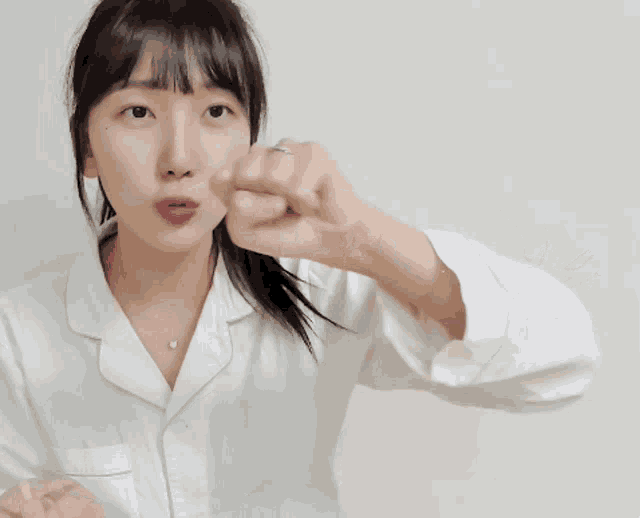 a woman wearing a white shirt is pointing her finger