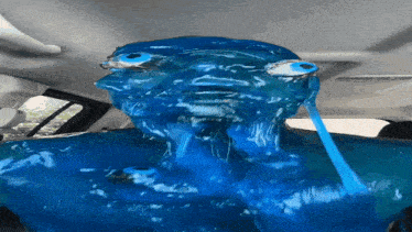 a person is covered in blue liquid with a hose coming out of it