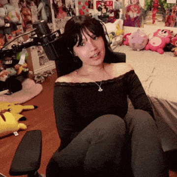 a woman sitting in front of a microphone with a necklace that says r on it