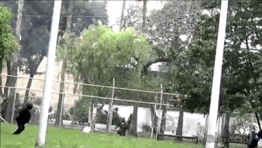a person is jumping over a fence in a park with the word universidad on the bottom right