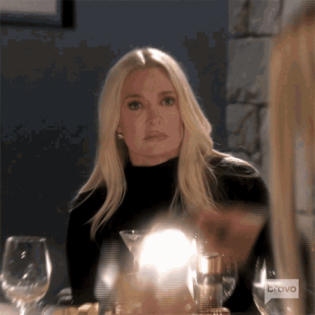 a woman is sitting at a table with a bravo logo on the bottom