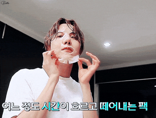 a man wearing a white shirt is applying a face mask