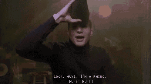 a man wearing a black turtleneck is holding a black hat on his head and talking .