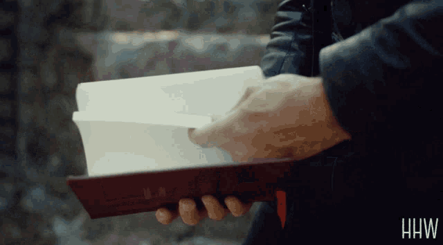 a person is holding a book in their hands with the letters hw on the bottom