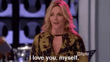 a woman is standing in front of a wall and saying `` i love you , myself '' .