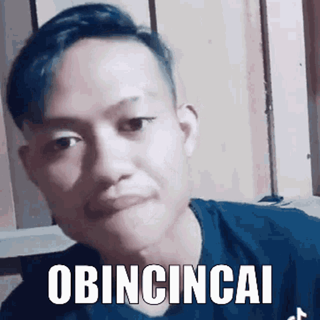 a man is wearing a black shirt and has the word obincincai written on his face .